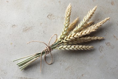 Photo of Bunch of wheat spikes on light grey table, top view