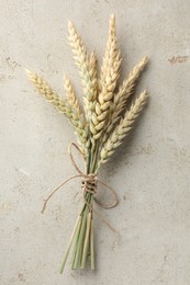 Photo of Bunch of wheat spikes on light grey table, top view