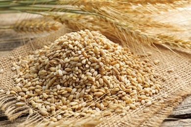 Photo of Wheat spikes and grains on wooden table, closeup