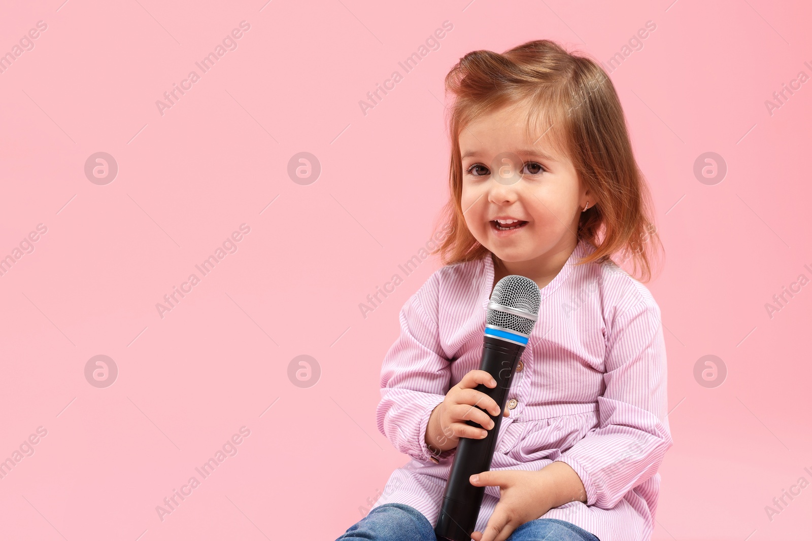 Cute little girl with microphone on pink background, space for text Photo of Cute little girl with microphone on pink background, space for text