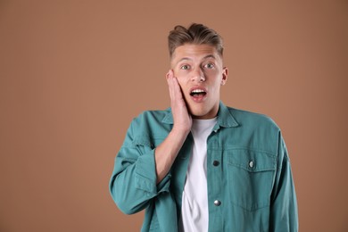 Photo of Portrait of surprised man on brown background, space for text