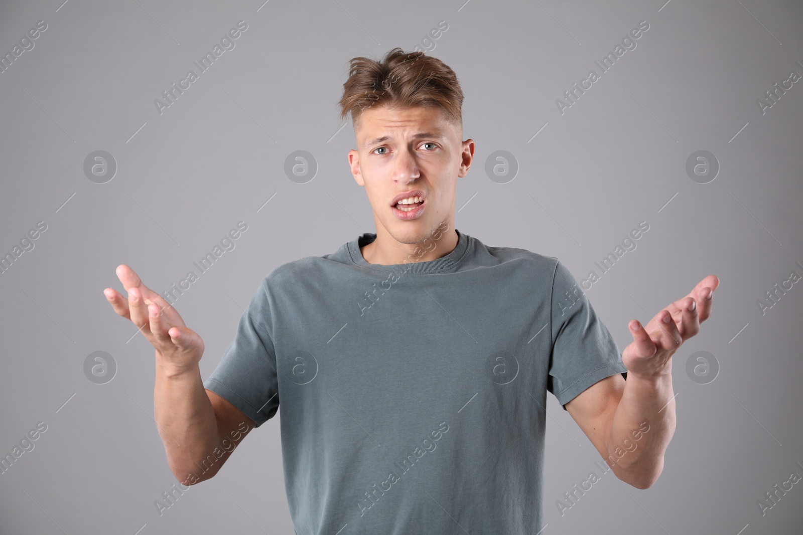 Portrait of confused man on grey background Photo of Portrait of confused man on grey background