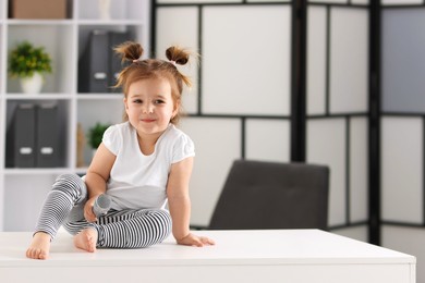 Photo of Cute little girl with microphone on white table at home, space for text