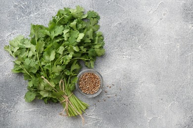 Photo of Fresh cilantro leaf and coriander seeds on grey table, top view. Space for text