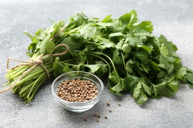 Photo of Fresh cilantro leaf and coriander seeds on grey table, closeup