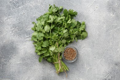 Photo of Fresh cilantro leaf and coriander seeds on grey table, top view