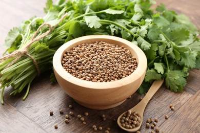Photo of Fresh cilantro and coriander seeds on wooden table, closeup