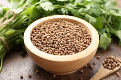 Photo of Fresh cilantro and coriander seeds on wooden table, closeup
