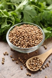 Photo of Fresh cilantro and coriander seeds on wooden table, closeup
