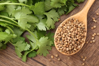 Photo of Fresh cilantro and coriander seeds on wooden table, top view