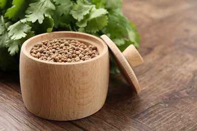 Photo of Fresh cilantro and coriander seeds on wooden table, closeup. Space for text