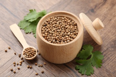 Photo of Fresh cilantro and coriander seeds on wooden table, closeup