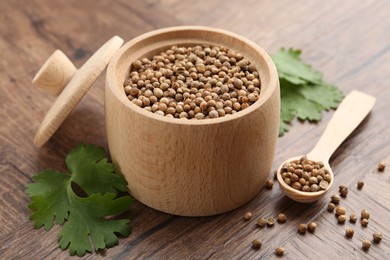 Photo of Fresh cilantro and coriander seeds on wooden table, closeup