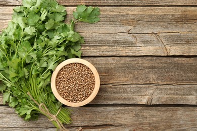 Photo of Fresh cilantro and coriander seeds on wooden table, top view. Space for text