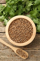 Photo of Fresh cilantro and coriander seeds on wooden table, top view