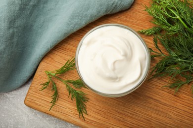 Photo of Tasty sour cream in bowl and dill on grey table, top view