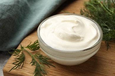 Photo of Tasty sour cream in bowl and dill on table, closeup