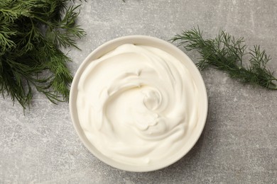 Photo of Tasty sour cream in bowl and dill on grey table, flat lay