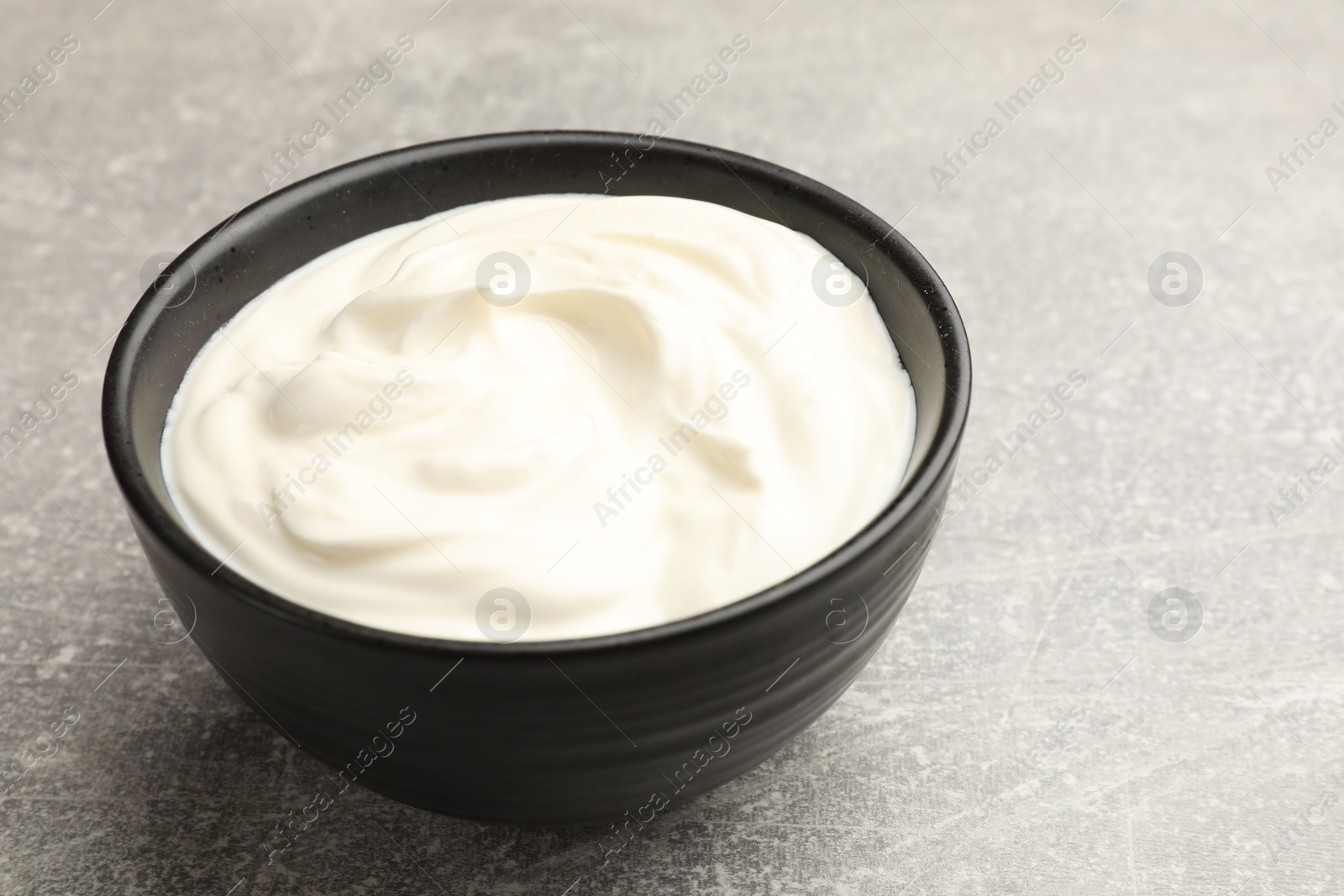 Tasty sour cream in bowl on grey table, closeup Photo of Tasty sour cream in bowl on grey table, closeup