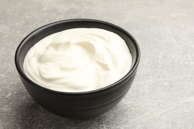 Photo of Tasty sour cream in bowl on grey table, closeup