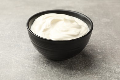 Photo of Tasty sour cream in bowl on grey table, closeup