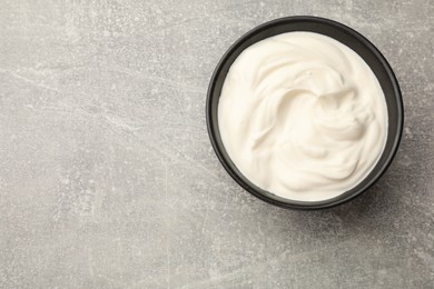 Photo of Tasty sour cream in bowl on grey table, top view. Space for text