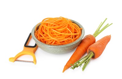Photo of Raw carrot noodles, peeler and fresh vegetables isolated on white. Vegetarian dish
