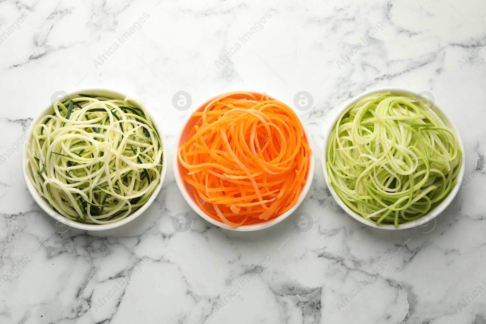 Different vegetable noodles in bowls on white marble table, flat lay. Vegetarian dish Photo of Different vegetable noodles in bowls on white marble table, flat lay. Vegetarian dish
