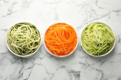 Photo of Different vegetable noodles in bowls on white marble table, flat lay. Vegetarian dish