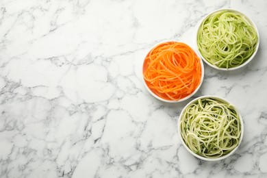 Photo of Vegetarian dish. Different vegetable noodles in bowls on white marble table, flat lay. Space for text