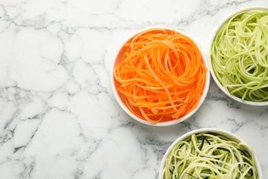 Photo of Vegetarian dish. Different vegetable noodles in bowls on white marble table, flat lay. Space for text