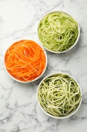Photo of Different vegetable noodles in bowls on white marble table, flat lay. Vegetarian dish
