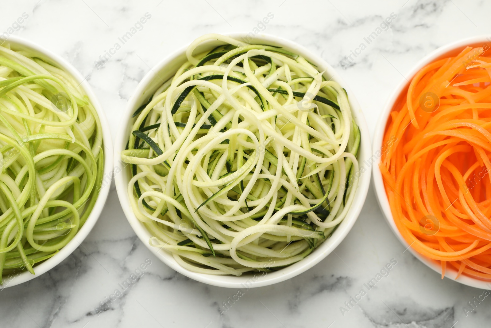 Different vegetable noodles in bowls on white marble table, flat lay. Vegetarian dish Photo of Different vegetable noodles in bowls on white marble table, flat lay. Vegetarian dish