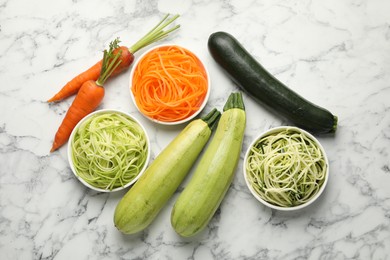 Photo of Different vegetarian noodles and fresh vegetables on white marble table, flat lay