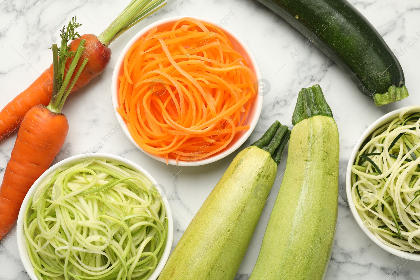 Different vegetarian noodles and fresh vegetables on white marble table, flat lay Photo of Different vegetarian noodles and fresh vegetables on white marble table, flat lay