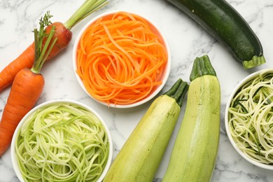 Photo of Different vegetarian noodles and fresh vegetables on white marble table, flat lay