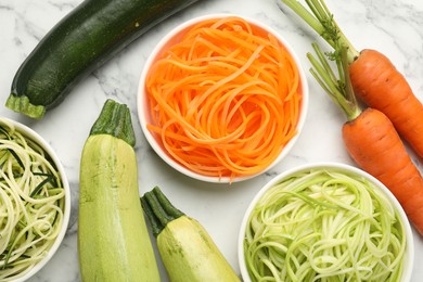 Photo of Different vegetarian noodles and fresh vegetables on white marble table, flat lay