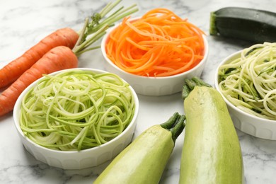 Photo of Different vegetarian noodles and fresh vegetables on white marble table, closeup
