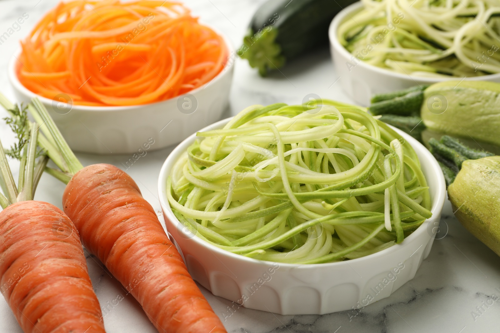 Different vegetarian noodles and fresh vegetables on white marble table, closeup Photo of Different vegetarian noodles and fresh vegetables on white marble table, closeup