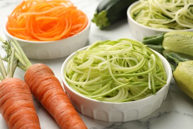 Photo of Different vegetarian noodles and fresh vegetables on white marble table, closeup