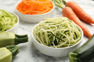 Photo of Different vegetarian noodles and fresh vegetables on white marble table, closeup