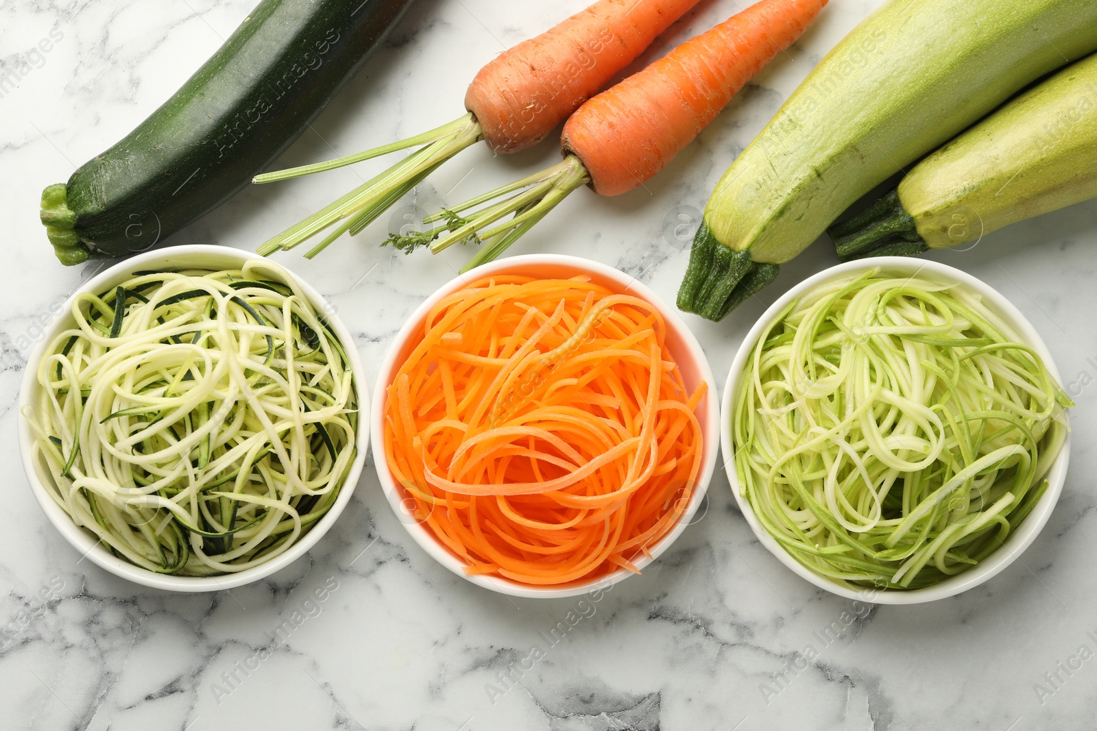 Different vegetarian noodles and fresh vegetables on white marble table, flat lay Photo of Different vegetarian noodles and fresh vegetables on white marble table, flat lay