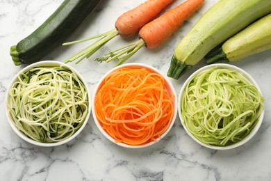 Photo of Different vegetarian noodles and fresh vegetables on white marble table, flat lay