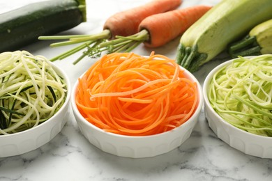 Photo of Different vegetarian noodles and fresh vegetables on white marble table, closeup