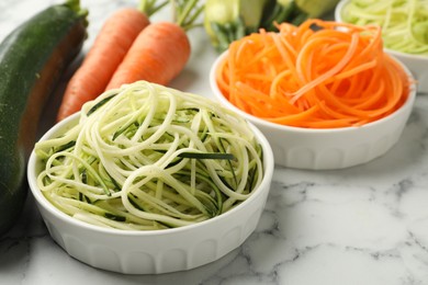 Photo of Different vegetarian noodles and fresh vegetables on white marble table, closeup