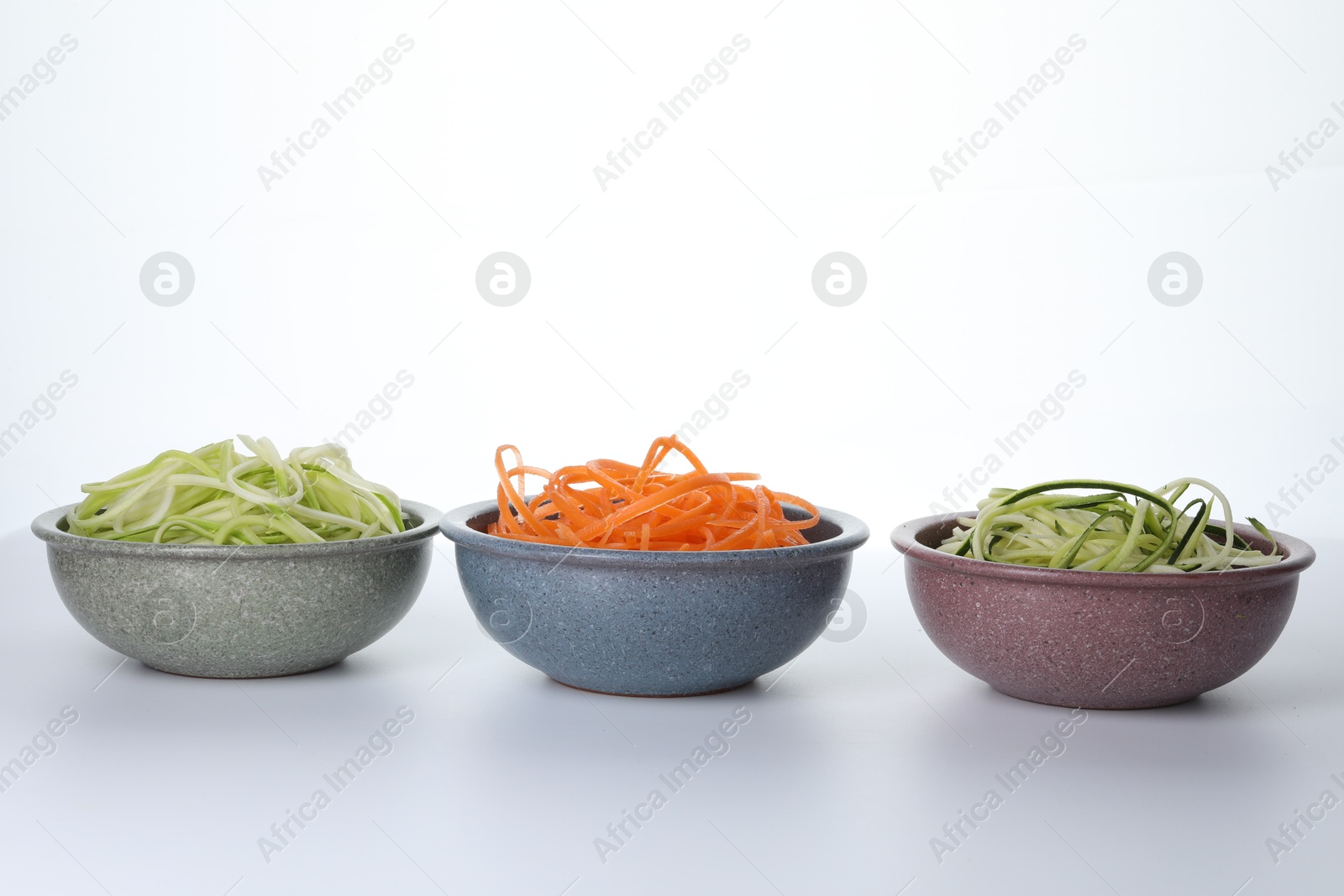 Different vegetable noodles in bowls on white background. Vegetarian dish Photo of Different vegetable noodles in bowls on white background. Vegetarian dish
