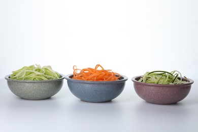 Photo of Different vegetable noodles in bowls on white background. Vegetarian dish