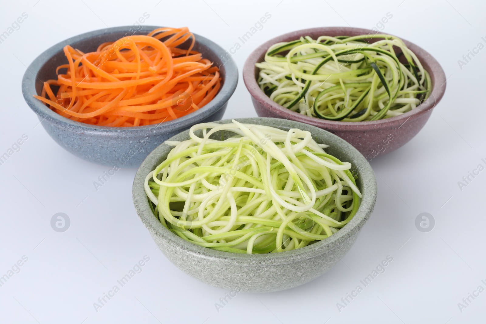 Different vegetable noodles in bowls on white background. Vegetarian dish Photo of Different vegetable noodles in bowls on white background. Vegetarian dish