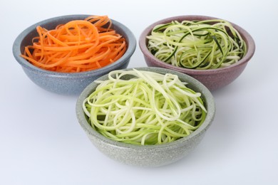 Photo of Different vegetable noodles in bowls on white background. Vegetarian dish