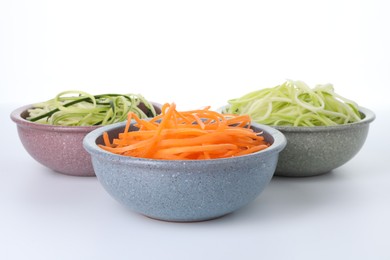 Photo of Different vegetable noodles in bowls on white background. Vegetarian dish